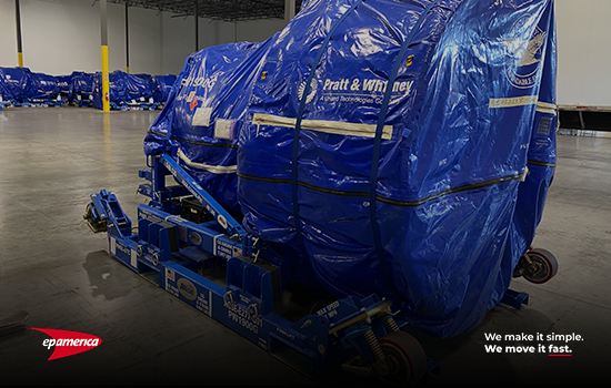 Image of the Pratt & Whitner aircraft engine correctly packed in a specific blue tarp and place over the structure to be correctly placed over the air ride flatbed unit.